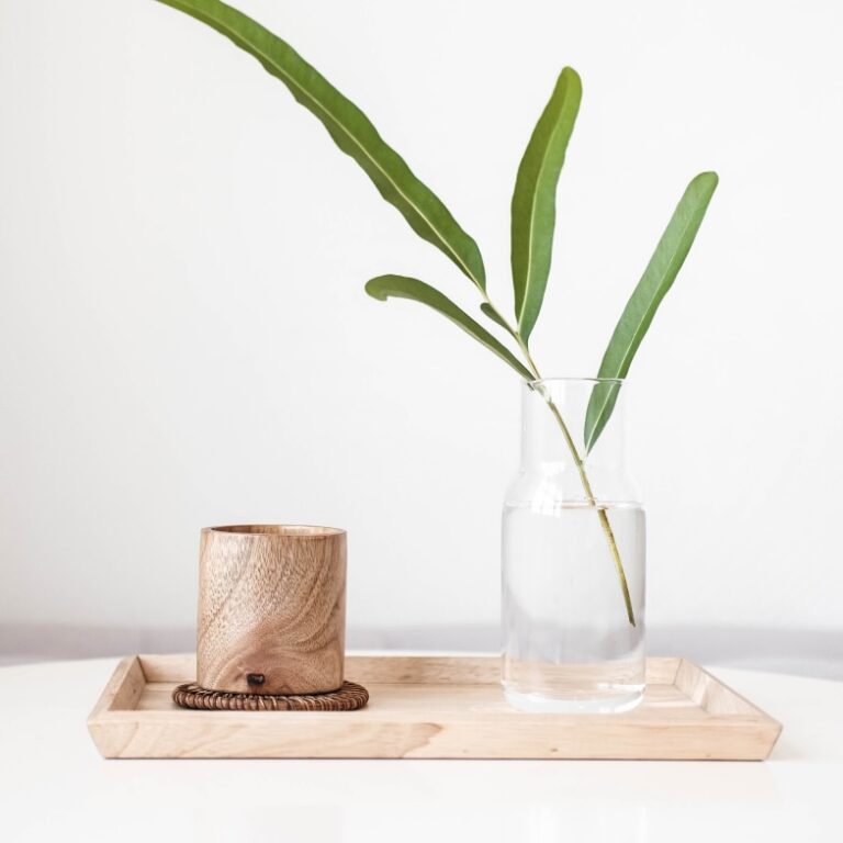 A wooden tray with a plant and a candle.