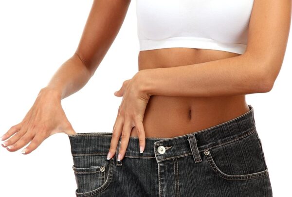 A woman is holding her stomach in her jeans.