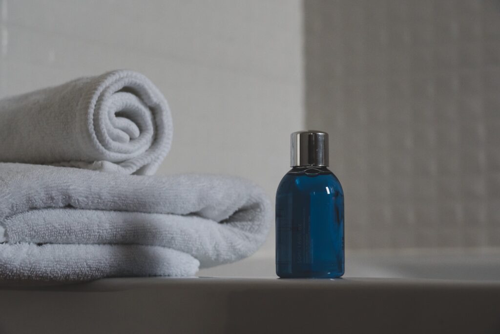 A bottle of water and a towel next to a bathtub.